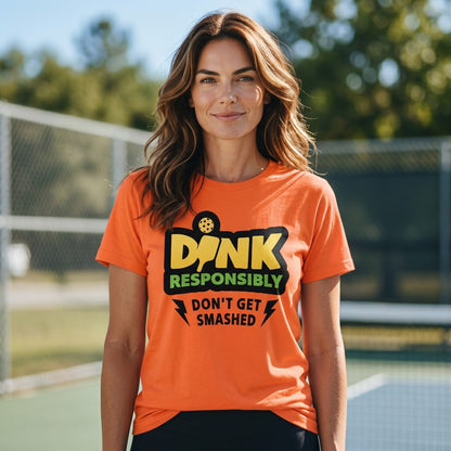  orange short sleeve t-shirt with Dink Responsibly pickleball graphic on a woman at a court